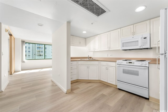 kitchen featuring a sink, white appliances, light wood-type flooring, light countertops, and recessed lighting