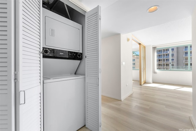 washroom with stacked washer / dryer, light wood-type flooring, baseboards, laundry area, and recessed lighting