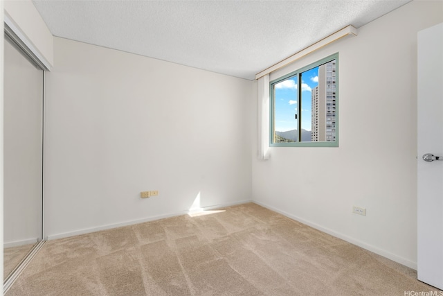 carpeted spare room featuring a textured ceiling and baseboards