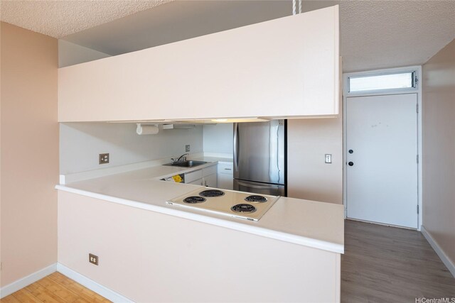 46-255 Kahuhipa St Unit A1204, Kaneohe, HI 96744 - kitchen featuring white electric stovetop, a peninsula, freestanding refrigerator, and a textured ceiling