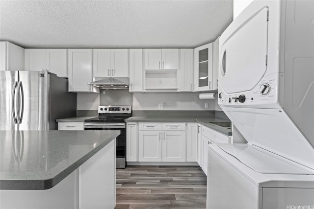 98-685 Kaonohi St Unit E, Aiea, HI 96701 - kitchen with stainless steel appliances, stacked washer / dryer, under cabinet range hood, white cabinetry, and dark wood-style flooring