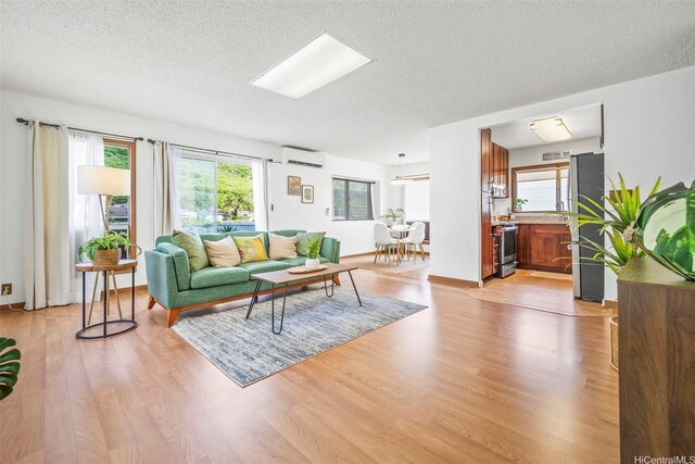 living area featuring light wood-style flooring, a textured ceiling, and a wall mounted air conditioner