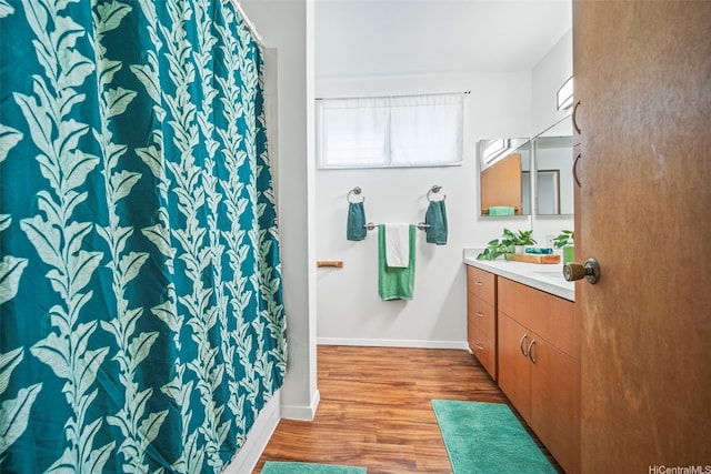full bath with baseboards, wood finished floors, curtained shower, and vanity