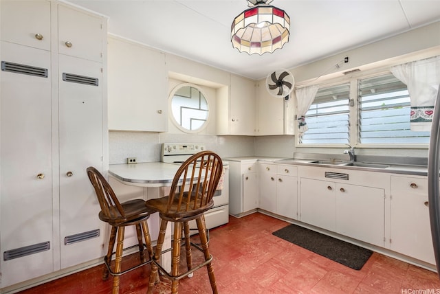 kitchen featuring white cabinets, a sink, white range with electric stovetop, stainless steel countertops, and light floors