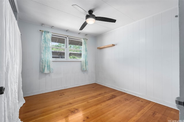 unfurnished room with a ceiling fan, baseboards, and light wood-type flooring