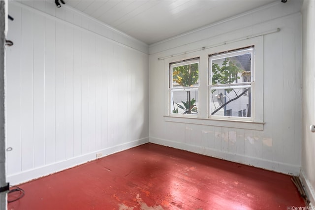 empty room featuring baseboards, wood finished floors, and crown molding
