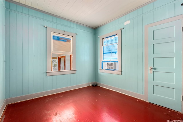 unfurnished room with wooden walls, cooling unit, and baseboards