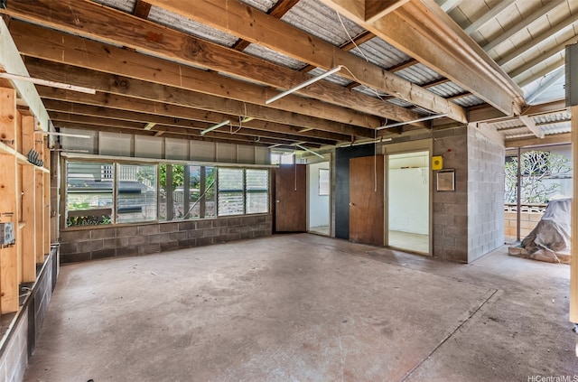 misc room with unfinished concrete flooring and concrete block wall