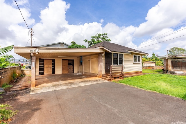 view of front of home with driveway, fence, an attached carport, and a front lawn