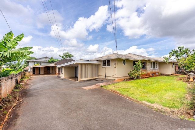 ranch-style house with a front lawn, a carport, fence, and aphalt driveway