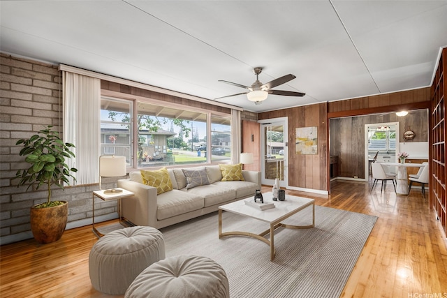 living room featuring wood walls, hardwood / wood-style flooring, ceiling fan, and plenty of natural light