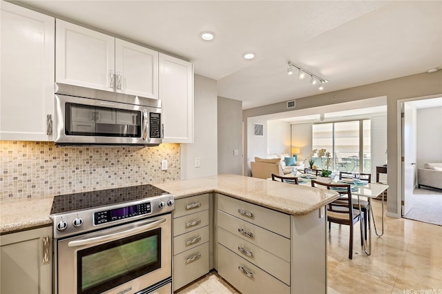 kitchen featuring white cabinets, a peninsula, appliances with stainless steel finishes, and tasteful backsplash