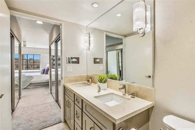 full bathroom with double vanity, toilet, a sink, and ensuite bathroom