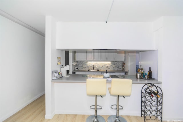 2600 Pualani Way Unit 1201, Honolulu, HI 96815 - kitchen featuring a peninsula, decorative backsplash, light wood-style floors, and a breakfast bar