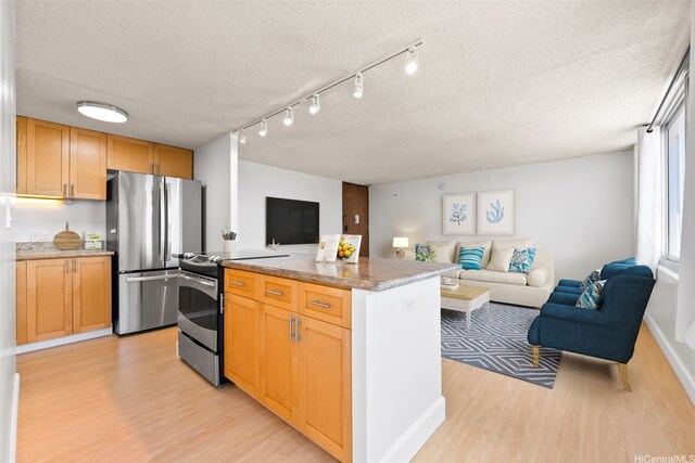 kitchen with a textured ceiling, open floor plan, stainless steel appliances, and light wood-style floors