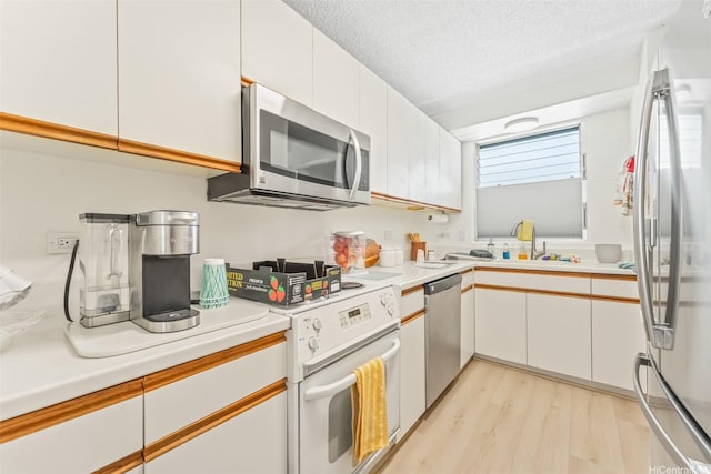 1615 Wilder Ave Unit 604, Honolulu, HI 96822 - kitchen with appliances with stainless steel finishes, a sink, light countertops, light wood-style flooring, and white cabinets