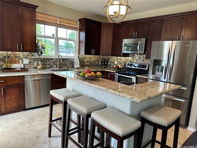 91-1005 Maulihiwa St, Kapolei, HI 96707 - kitchen with stainless steel appliances, decorative backsplash, light stone counters, dark brown cabinets, and a breakfast bar