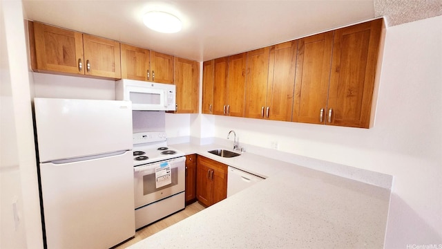 kitchen featuring white appliances, brown cabinetry, a sink, and light countertops