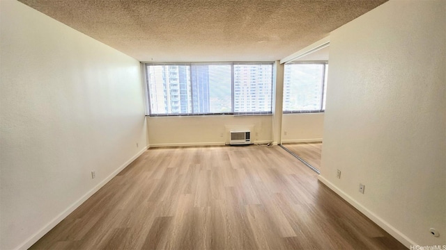 unfurnished room with a textured ceiling, baseboards, and wood finished floors