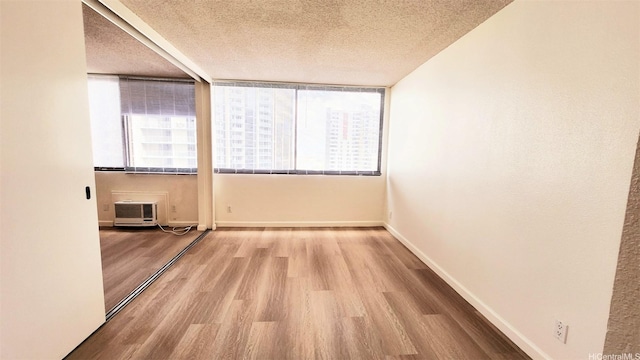 unfurnished room with baseboards, a textured ceiling, and wood finished floors