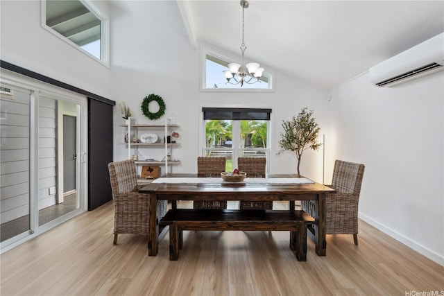 dining space with high vaulted ceiling, an inviting chandelier, light wood-style flooring, and a wall unit AC