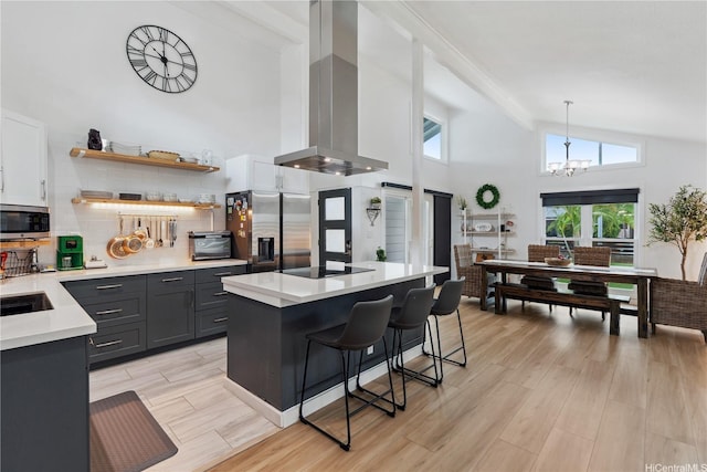 kitchen with stainless steel appliances, light countertops, island range hood, a breakfast bar area, and a notable chandelier