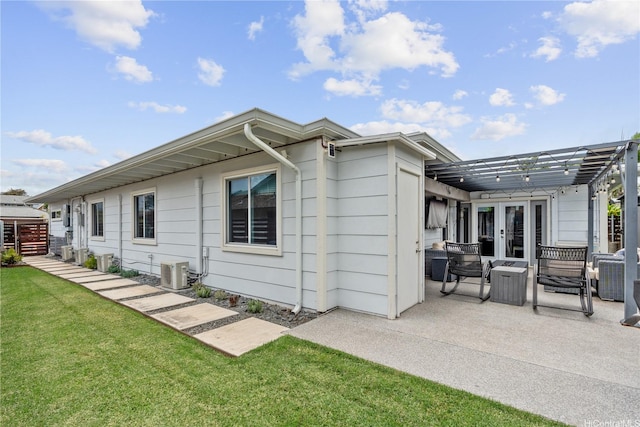 rear view of property featuring french doors, central AC unit, a pergola, a patio area, and a yard