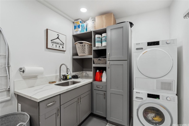 laundry room with cabinet space, stacked washing maching and dryer, and a sink