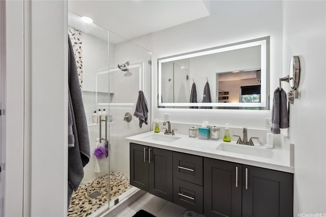 bathroom featuring tile patterned floors, a sink, double vanity, and a stall shower