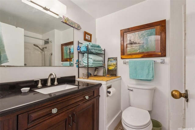 bathroom featuring a tile shower, vanity, and toilet