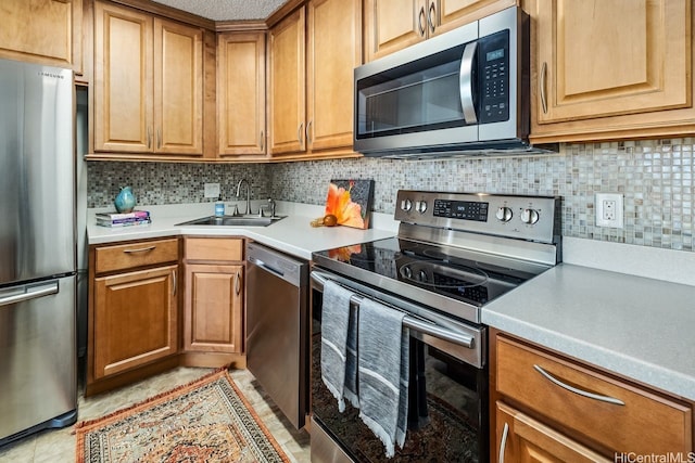 kitchen featuring brown cabinetry, a sink, backsplash, and stainless steel appliances