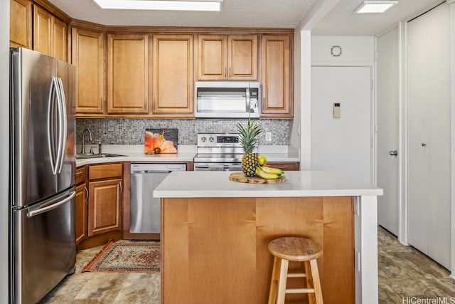 kitchen with brown cabinets, a sink, stainless steel appliances, light countertops, and backsplash