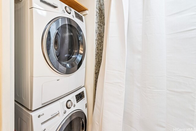 clothes washing area featuring stacked washer and clothes dryer and laundry area