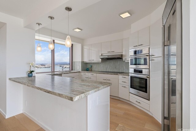 425 S St Unit 2004, Honolulu, HI 96813 - kitchen with a peninsula, under cabinet range hood, black electric stovetop, and white cabinets