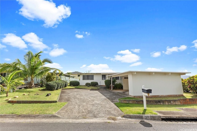 ranch-style home featuring a front yard, an attached carport, and aphalt driveway
