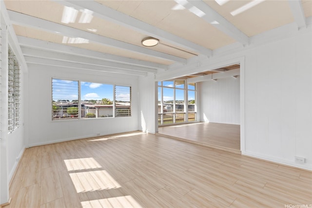 empty room featuring beam ceiling, wood finished floors, and baseboards