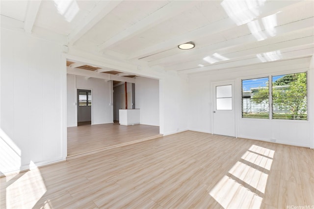 empty room with light wood-style floors and beamed ceiling