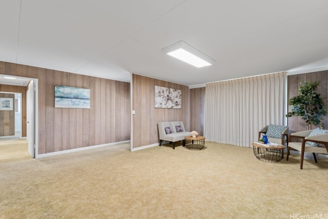 sitting room featuring wooden walls and carpet
