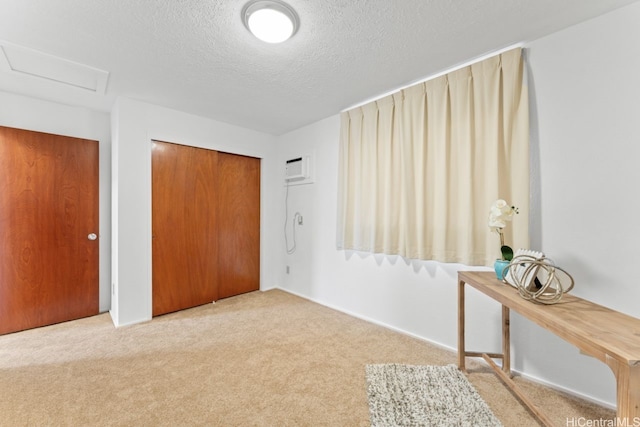 unfurnished bedroom with a wall mounted air conditioner, a textured ceiling, a closet, and carpet