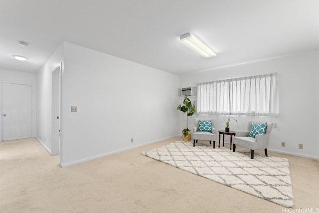 sitting room with a wall unit AC, carpet, and baseboards