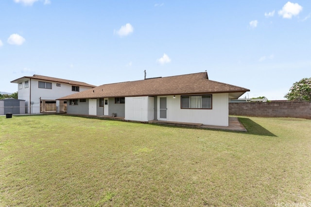 back of house featuring a lawn, a shingled roof, and a fenced backyard