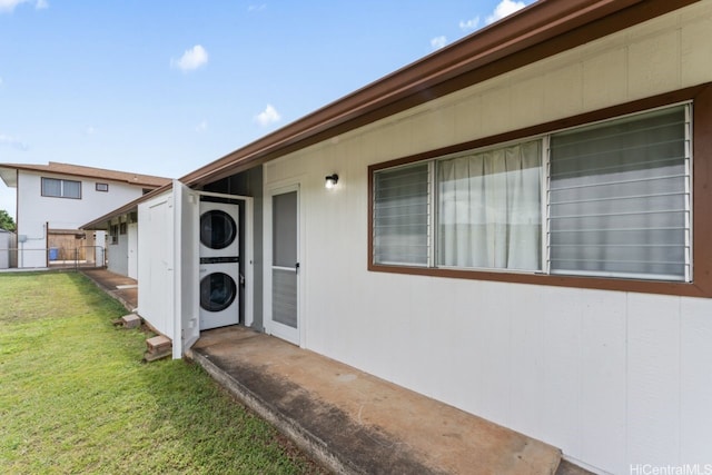doorway to property featuring fence, stacked washing maching and dryer, and a yard