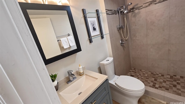 full bath featuring vanity, toilet, and tiled shower