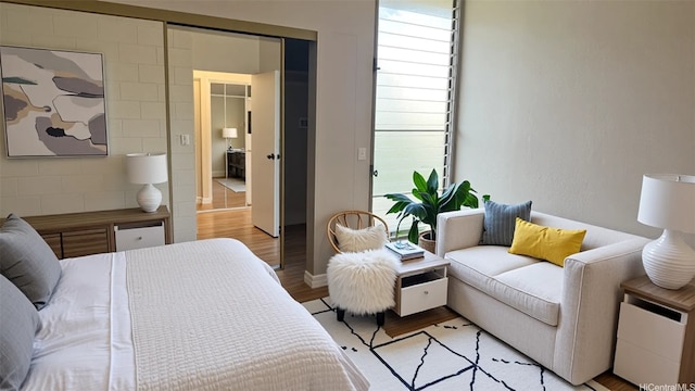 bedroom with a closet, baseboards, multiple windows, and light wood-style floors