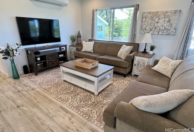 living area with wood finished floors, a wealth of natural light, and a wall unit AC
