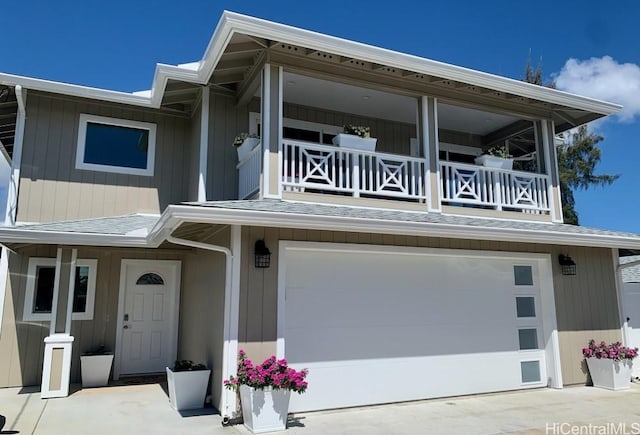 view of front of property with concrete driveway, a shingled roof, a balcony, and a garage