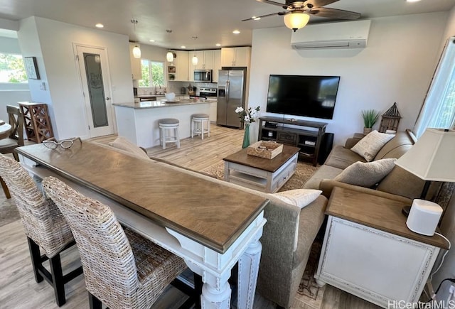 living room featuring a wall mounted air conditioner, a ceiling fan, light wood-style floors, and recessed lighting