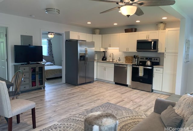 kitchen featuring appliances with stainless steel finishes, open floor plan, ceiling fan, and a sink