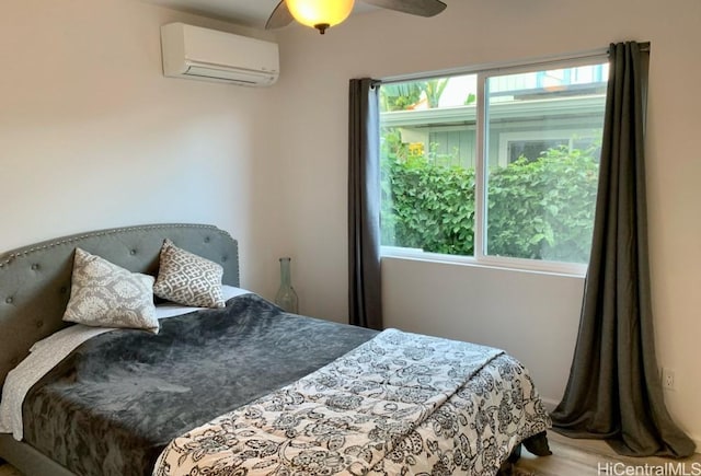 bedroom with a wall mounted air conditioner, wood finished floors, a ceiling fan, and multiple windows
