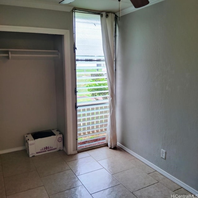 interior space with crown molding, light tile patterned flooring, baseboards, and a ceiling fan